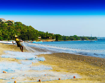 Fisherman casting net on sea shore