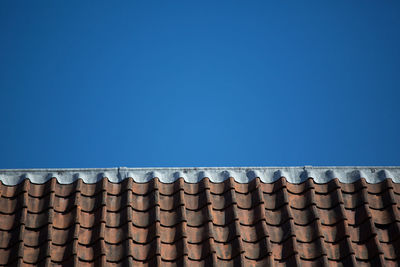 Low angle view of roof tiles against blue sky