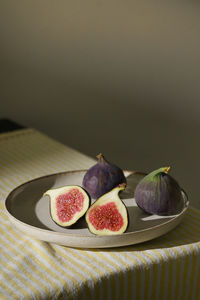 Figs fruits placed on a small plate on a table with a tablecloth and sunshine