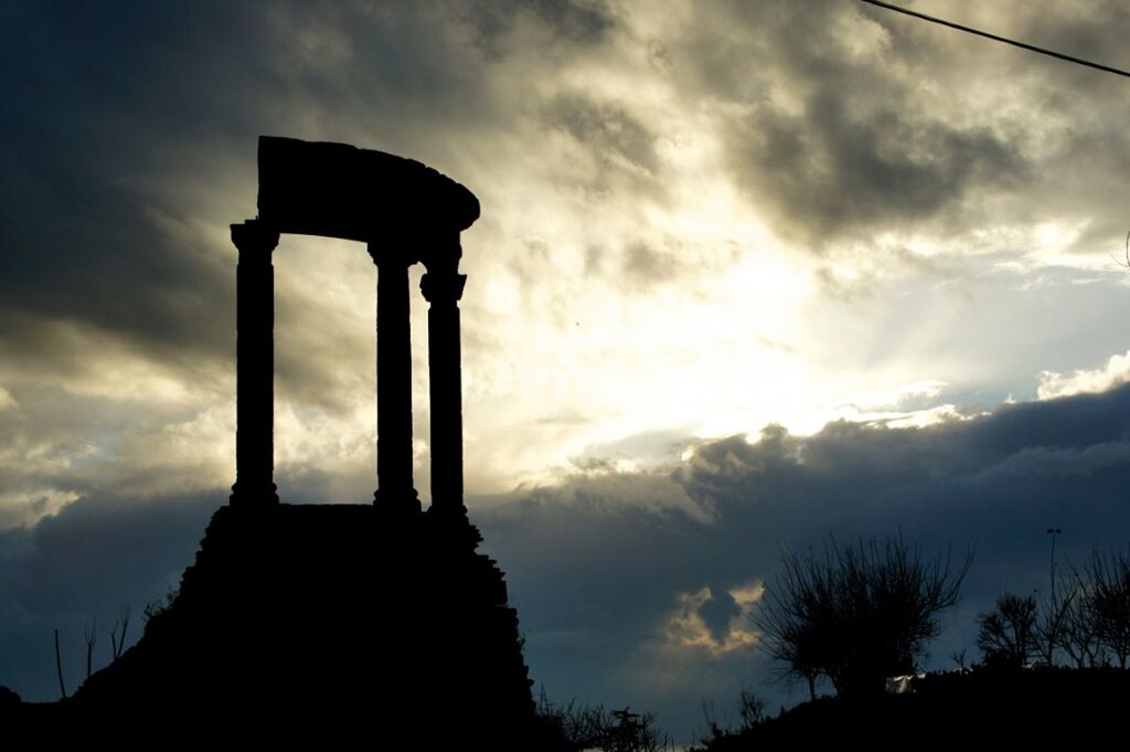 low angle view, silhouette, sky, cloud - sky, sunset, built structure, architecture, cloud, cloudy, building exterior, dusk, sun, religion, outdoors, no people, spirituality, architectural column, sunlight, street light