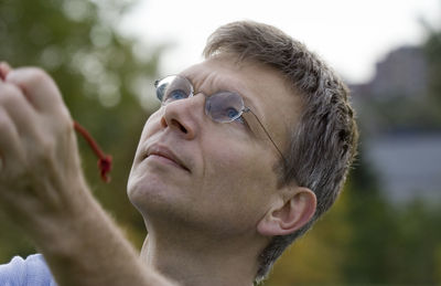 Close-up of mature man looking up while holding string