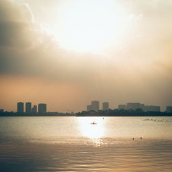 Sea and buildings against sky during sunset