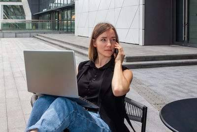 Young business woman working at the computer outside, makes the phone call