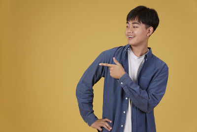 Young man standing against yellow background