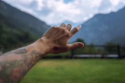 Cropped hand of man reaching mountains