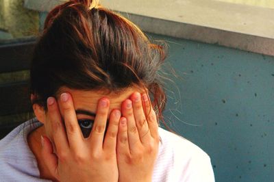 Close-up of young woman hiding face with hand