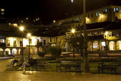 Illuminated buildings by street in city at night