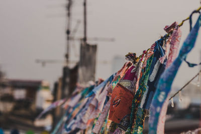 Close-up of clothes hanging on metal structure against sky