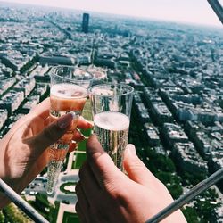 Cropped hands toasting champagne flutes against cityscape