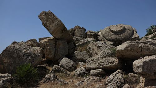 Low angle view of rocks against clear blue sky