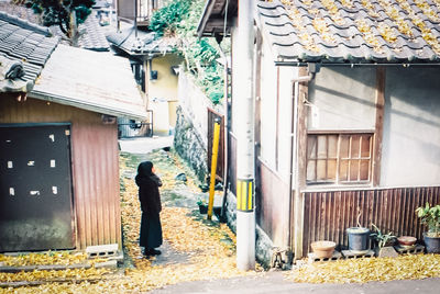 Rear view of man walking on street amidst buildings