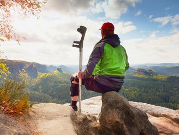 Rear view of man standing on rock against sky