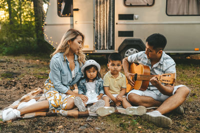 An asian family is vacationing traveling on a road trip by a camper car in the forest in nature