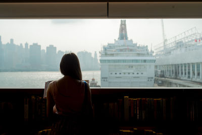 Rear view of woman standing in library against sky