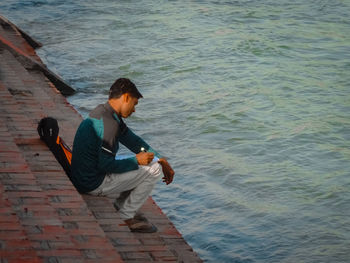 High angle view of man sitting at sea shore