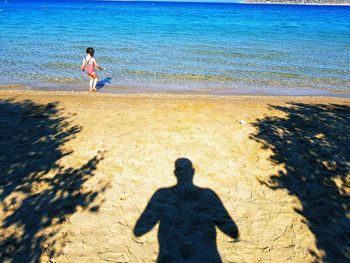 Rear view of girl standing by shadow at beach