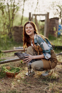 Portrait of young woman holding hen at poultry farm