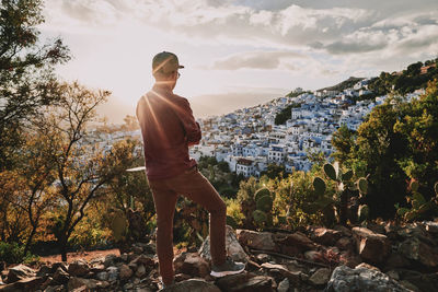 Full length of man standing on rock against sky during sunset