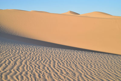 Sand dunes in desert against clear sky