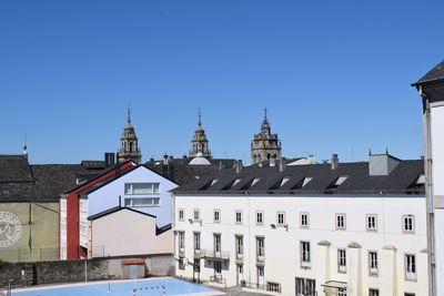 Buildings in city against clear blue sky