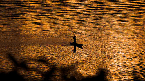 Silhouette person on sea against sky during sunset