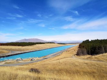 Scenic view of road by land against blue sky