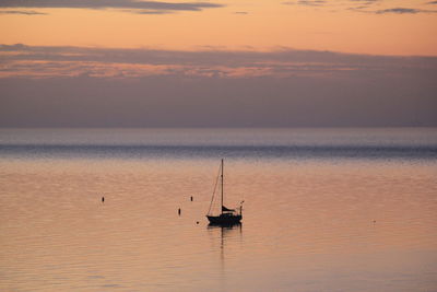 Sailboat in sea against sky during sunset