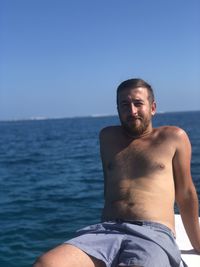 Portrait of shirtless man in sea against clear sky