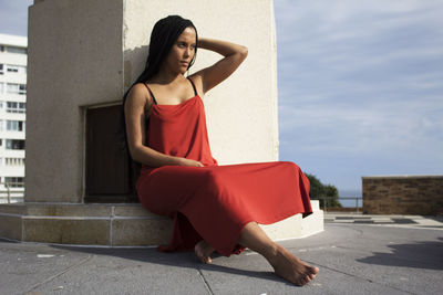 Young woman sitting with red umbrella