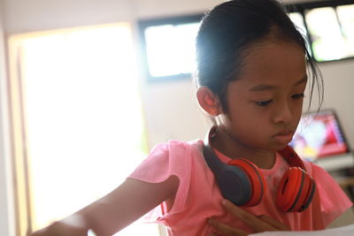 Close-up of girl wearing headphones while sitting at home