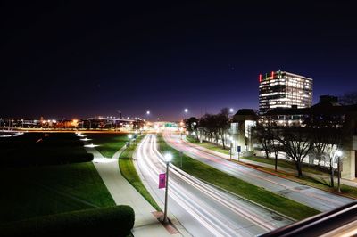 Light trails on road amidst buildings in city at night