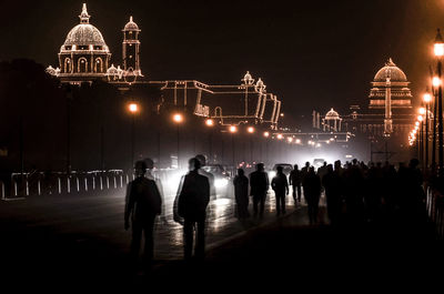 People at illuminated temple against sky at night