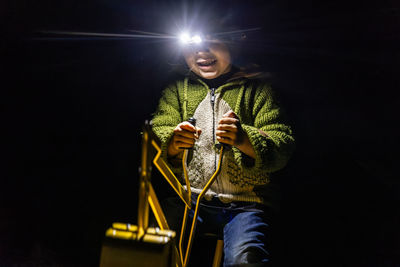 Low angle view of woman standing against black background