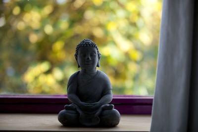 Close-up of buddha statue on widow sill