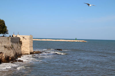 Trani, italy, 4 december 2022, public gardens, the medieval wall and the pier of san nicola