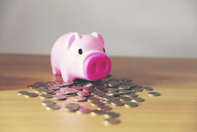 Close-up of coins with piggy bank on wooden table