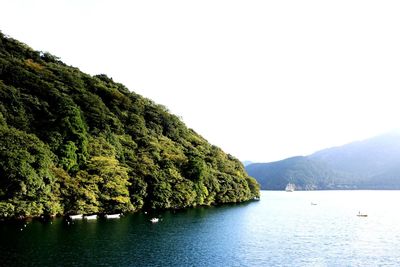 Scenic view of sea by mountains against clear sky