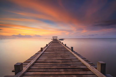 Pier over sea against sky during sunset