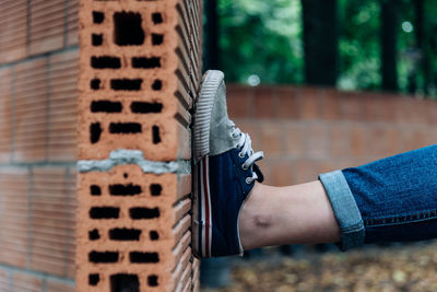 Close-up of leg on curved brick wall