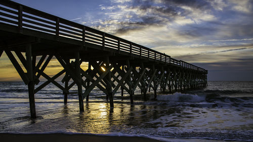 Pier over sea against sky during sunset