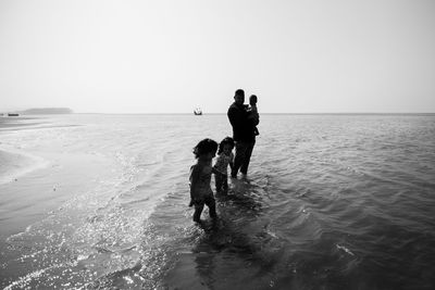 People on beach against clear sky