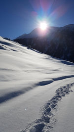 Scenic view of snow covered mountains against bright sun