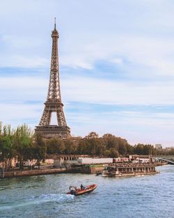 View of eiffel tower by river against sky