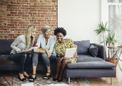 Friends sitting on sofa at home