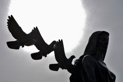 Low angle view of silhouette woman standing against sky