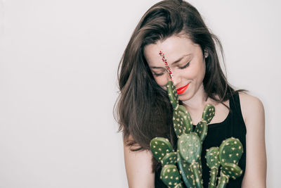 Close-up of woman with cactus against white background