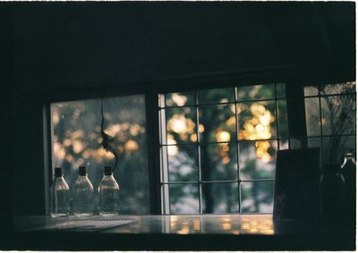 Glass bottles on table by glass window
