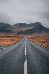 Road leading towards mountains against sky