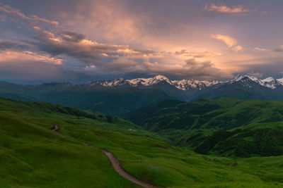 Beautiful green mountains with snowy peaks at sunset