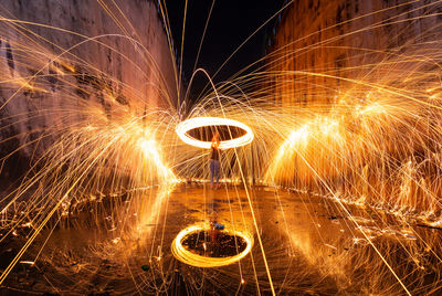 Man spinning wire wool while standing on street at night